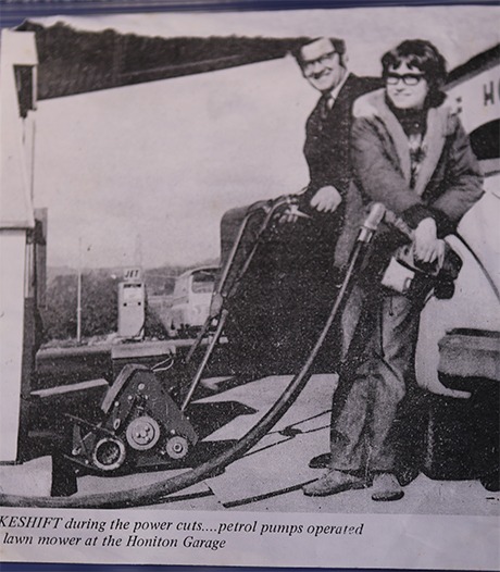 Newspaper photograph from 1972 of petrol pumps being operated by a lawn mower at the Honiton Garage during the power cuts