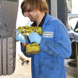 Mechanic in Honiton Garage overalls using an impact wrench on a wheel