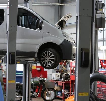 A van raised on a two-post lift in our workshop