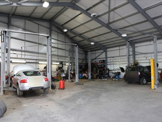 Wide view of the workshop with two-post lifts and cars in for work